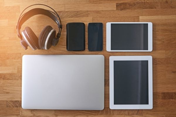 laptop, cell phones, tablets, and headphones on a table